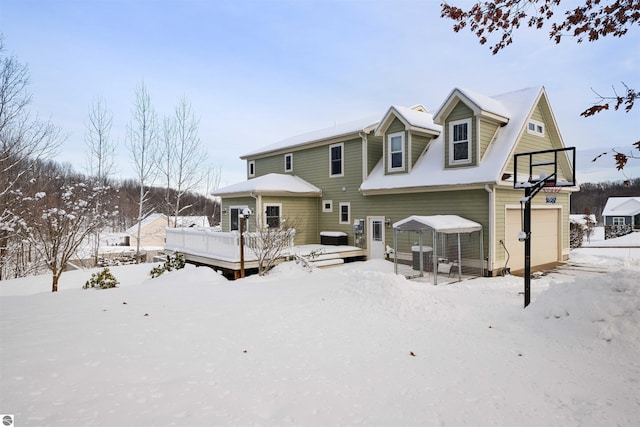 snow covered property with a garage and a deck