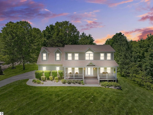 colonial-style house featuring covered porch and a lawn