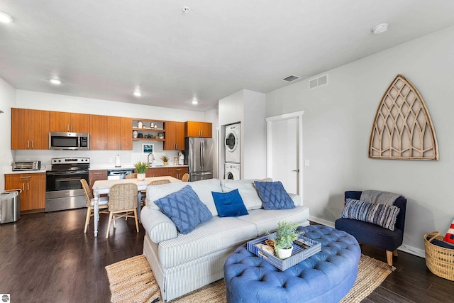 living room with dark wood-type flooring and stacked washer and dryer