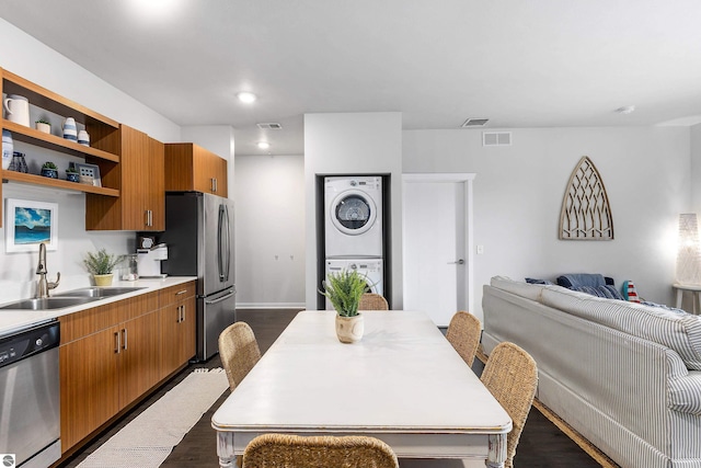 kitchen with dark hardwood / wood-style flooring, stacked washer and dryer, stainless steel appliances, and sink