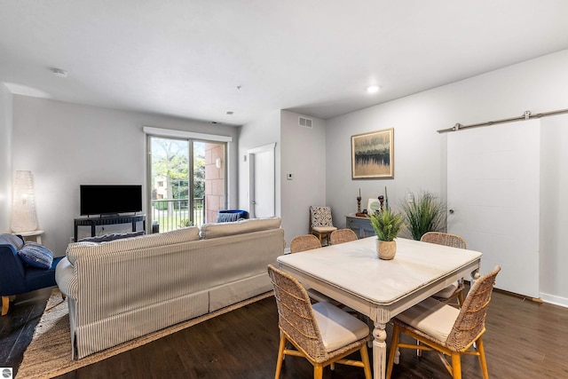 dining space featuring dark hardwood / wood-style floors and a barn door