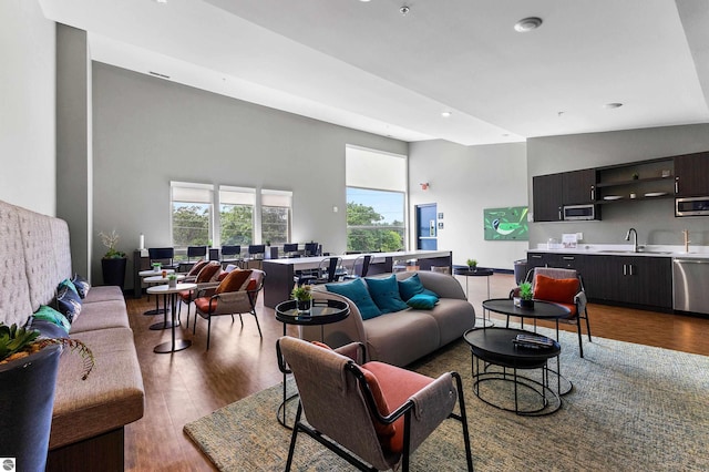 living room featuring sink, hardwood / wood-style floors, and high vaulted ceiling