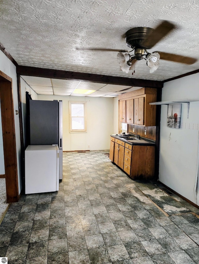 kitchen featuring sink, a textured ceiling, stainless steel fridge, and ceiling fan