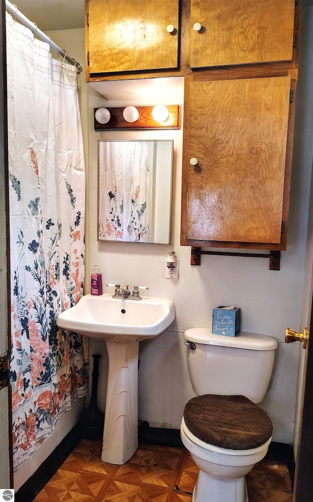 bathroom featuring parquet floors and toilet