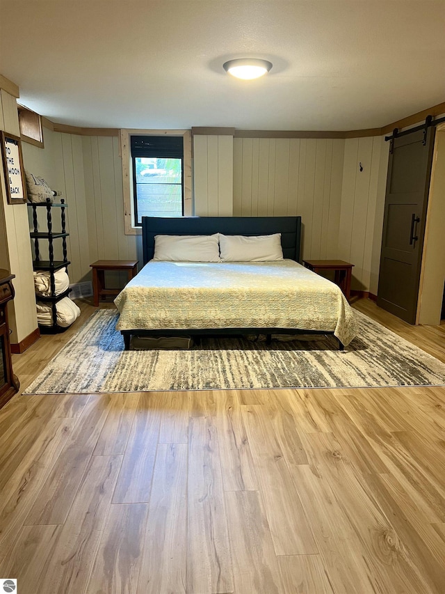 bedroom featuring a barn door and light wood-type flooring