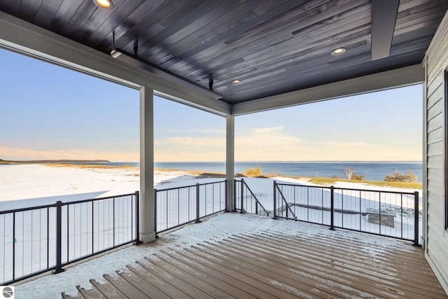 deck at dusk featuring a water view and a beach view