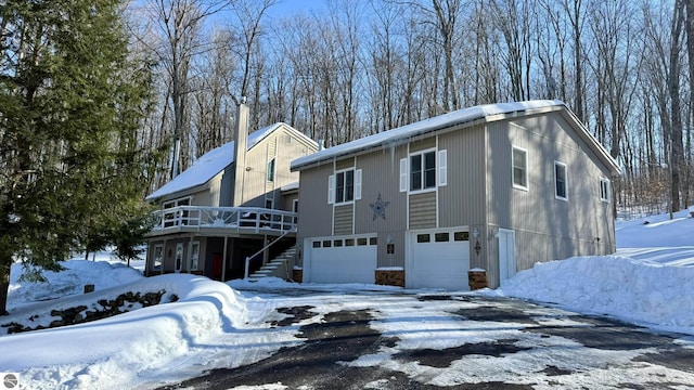 view of snowy exterior with a garage and a wooden deck