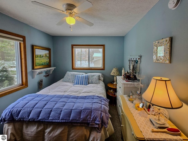 carpeted bedroom with ceiling fan and a textured ceiling