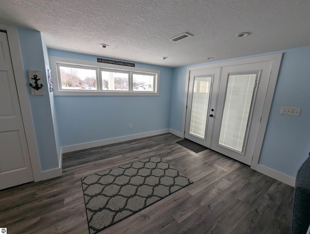 foyer with french doors, dark hardwood / wood-style flooring, and a textured ceiling