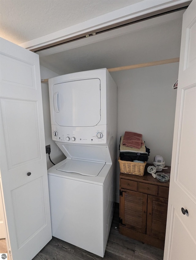 washroom with dark wood-type flooring and stacked washer and dryer