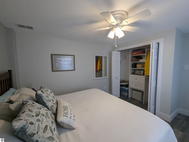 bedroom featuring dark wood-type flooring, a textured ceiling, ceiling fan, and a closet