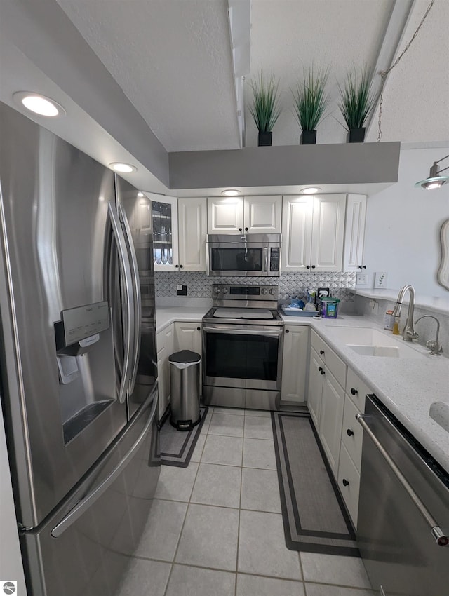 kitchen with stainless steel appliances, sink, decorative backsplash, and white cabinets