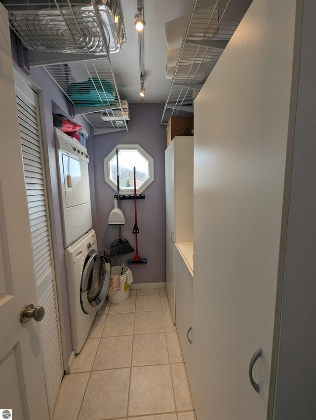 laundry room with stacked washer and dryer and light tile patterned floors