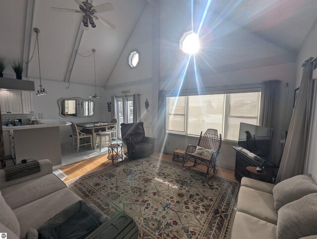 living room with light hardwood / wood-style flooring, high vaulted ceiling, and ceiling fan