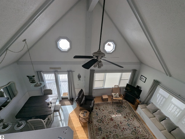 tiled living room featuring ceiling fan, high vaulted ceiling, and a textured ceiling