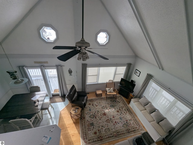 living room featuring ceiling fan, high vaulted ceiling, and light hardwood / wood-style flooring