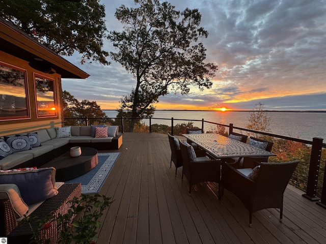 deck at dusk with outdoor lounge area and a water view