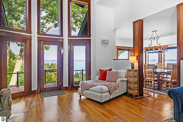 interior space featuring a notable chandelier, hardwood / wood-style flooring, a towering ceiling, and a water view