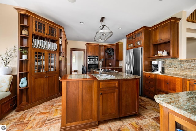 kitchen featuring decorative light fixtures, a center island with sink, stainless steel appliances, light stone countertops, and decorative backsplash