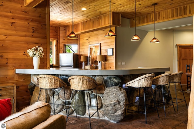 bar featuring wood ceiling, stainless steel refrigerator, decorative light fixtures, and wood walls