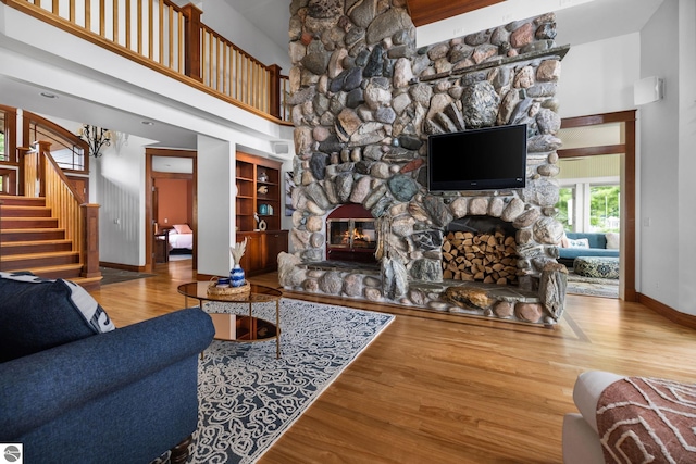 living room featuring a towering ceiling, a fireplace, and wood-type flooring