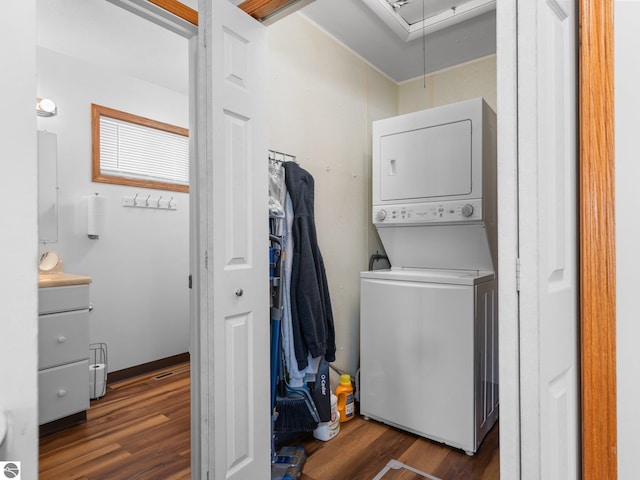 washroom featuring stacked washer and dryer and dark wood-type flooring