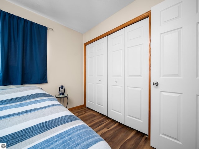 bedroom with dark hardwood / wood-style floors and a closet