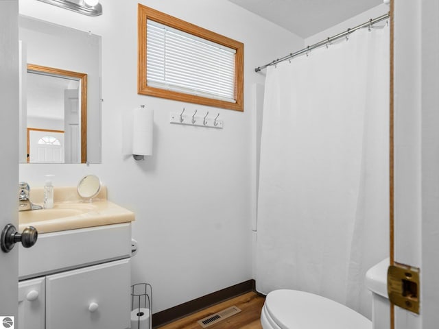 bathroom with hardwood / wood-style flooring, vanity, a shower with curtain, and toilet