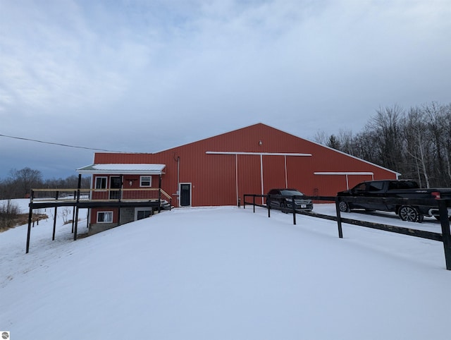 snow covered back of property with an outbuilding, a garage, and an outdoor structure