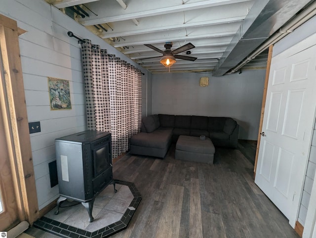 living room featuring ceiling fan, a wood stove, and dark hardwood / wood-style flooring