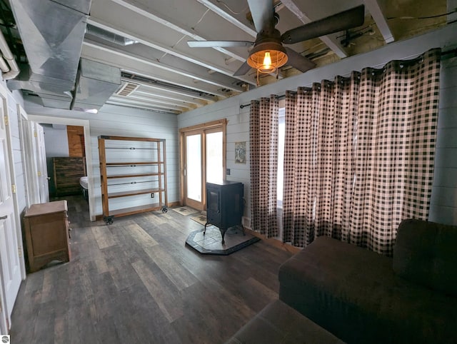 interior space with wood-type flooring, a wood stove, and ceiling fan