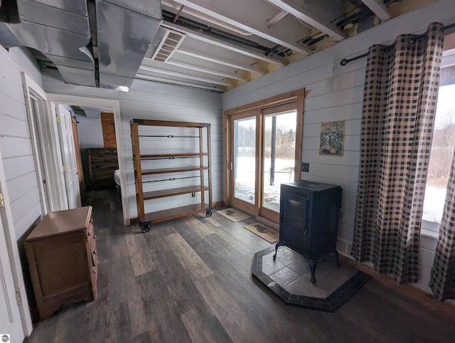 interior space featuring wooden walls, dark hardwood / wood-style flooring, and a wood stove