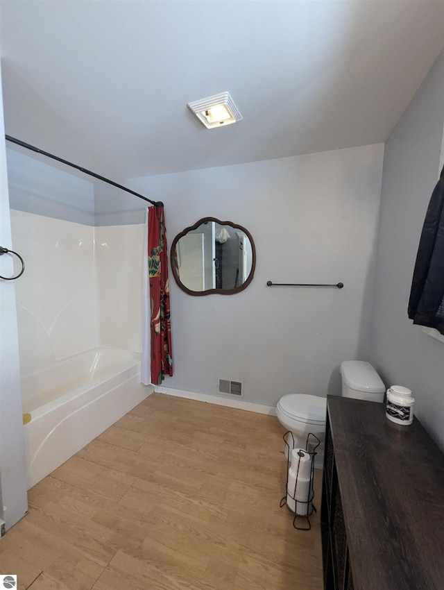 bathroom with shower / tub combo, toilet, and hardwood / wood-style floors