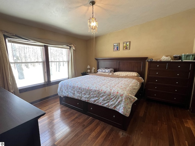 bedroom with dark hardwood / wood-style floors, a textured ceiling, and a notable chandelier