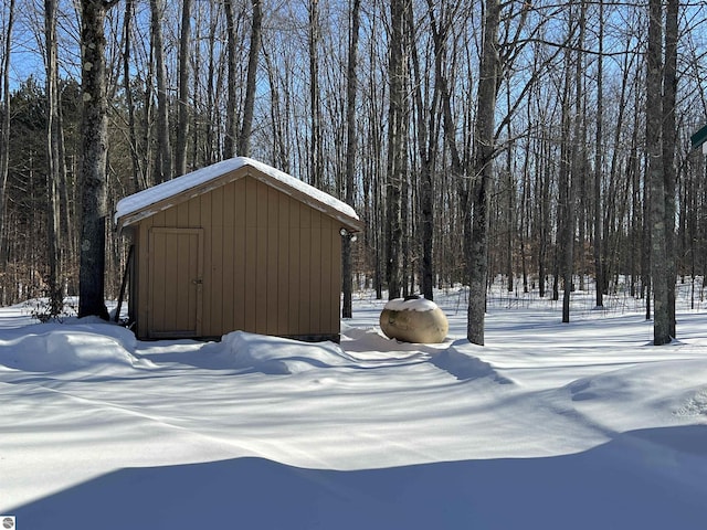 snowy yard featuring a storage shed