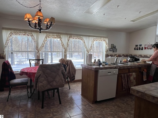 dining room featuring an inviting chandelier, sink, a textured ceiling, and dark tile patterned floors