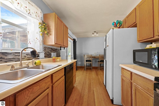 kitchen featuring light hardwood / wood-style flooring, sink, decorative backsplash, and black appliances