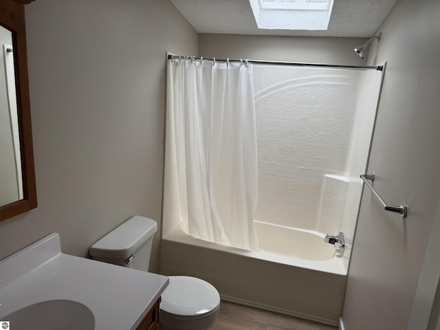 full bathroom featuring a skylight, vanity, shower / bath combination with curtain, a textured ceiling, and toilet