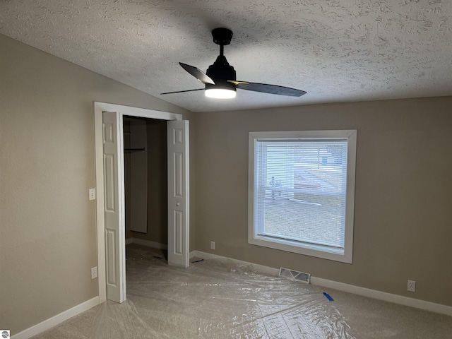 unfurnished bedroom featuring lofted ceiling, ceiling fan, a textured ceiling, light carpet, and a closet