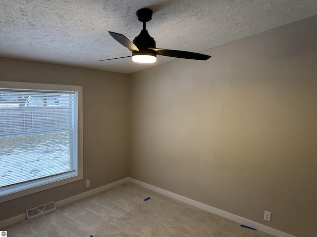 carpeted empty room with ceiling fan and a textured ceiling