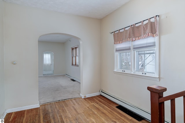 empty room featuring a baseboard heating unit and light wood-type flooring