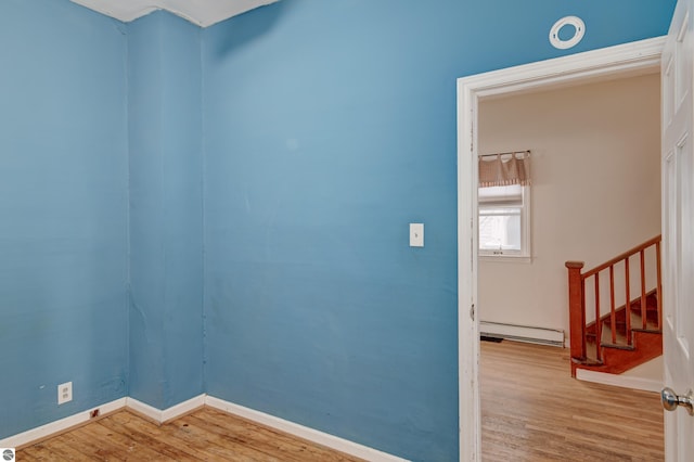 empty room featuring light wood-type flooring and a baseboard heating unit