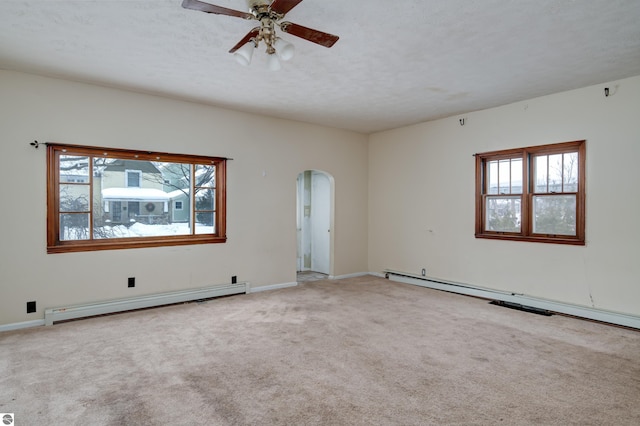 carpeted spare room featuring ceiling fan, a wealth of natural light, a textured ceiling, and a baseboard heating unit