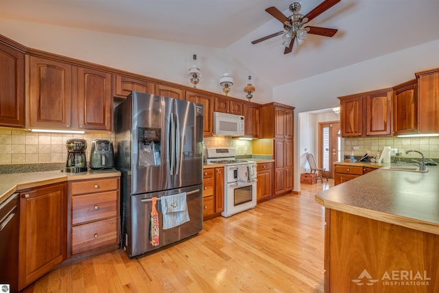 kitchen featuring vaulted ceiling, sink, backsplash, stainless steel appliances, and light wood-type flooring