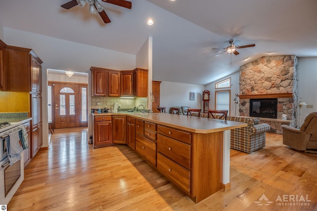 kitchen featuring ceiling fan, sink, light wood-type flooring, and kitchen peninsula