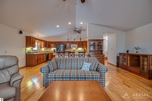 living room with lofted ceiling, sink, light hardwood / wood-style flooring, and ceiling fan