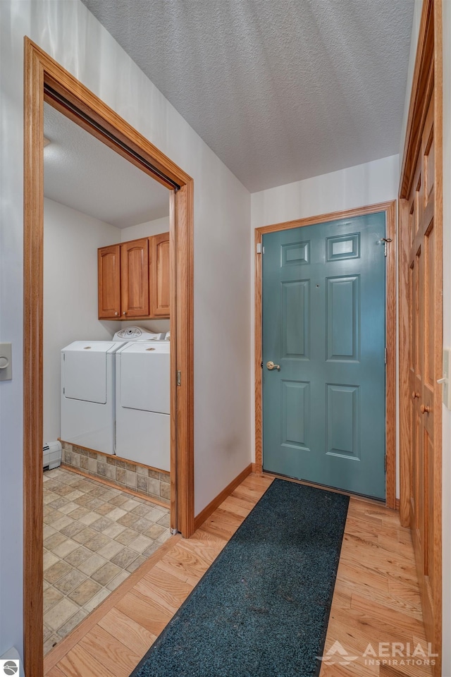 foyer entrance featuring washer and clothes dryer, light hardwood / wood-style floors, a textured ceiling, and a baseboard heating unit