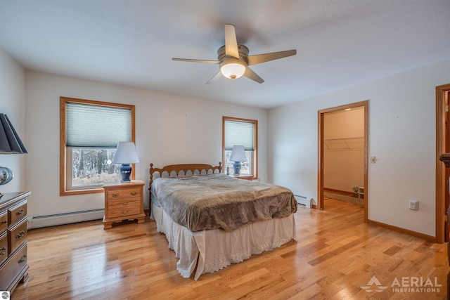 bedroom featuring a baseboard radiator, a spacious closet, ceiling fan, and light wood-type flooring