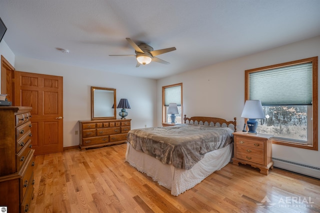 bedroom featuring a baseboard radiator, multiple windows, and light hardwood / wood-style flooring