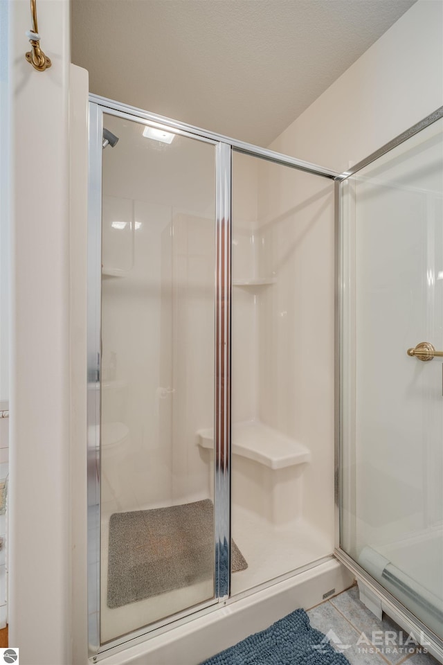 bathroom with an enclosed shower and tile patterned floors